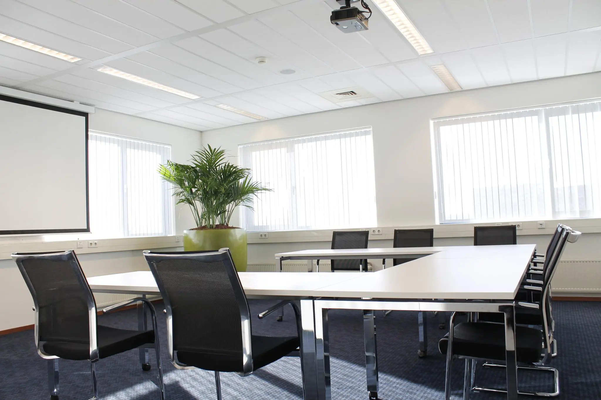 Vergaderruimte aan de Laan van s-Gravenmade met moderne inrichting, grote ramen en een projector.